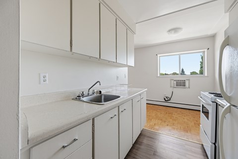 A kitchen with white cabinets and a window.