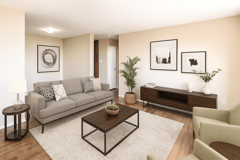A living room with a grey couch, a coffee table, a side table, a chair, a potted plant, and pictures on the wall.