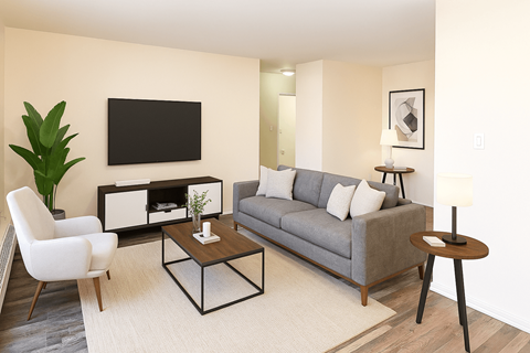 A living room with a grey couch, a white chair, a black coffee table, and a flat screen TV mounted on the wall.