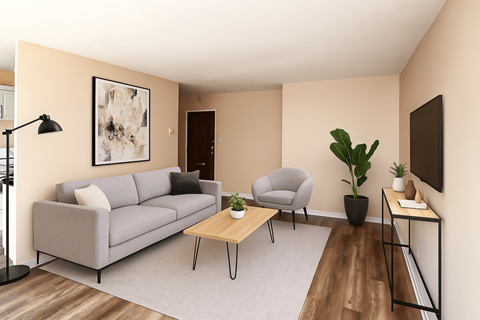 A living room with a grey couch, a grey armchair, a wooden coffee table, and a painting on the wall.