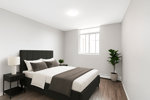 A bedroom with a large bed and a potted plant.