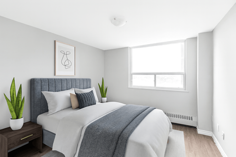 A bedroom with a bed, pillows, a blanket, a nightstand, and a window.