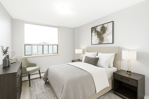 A bedroom with a large bed, a chair, and a window.