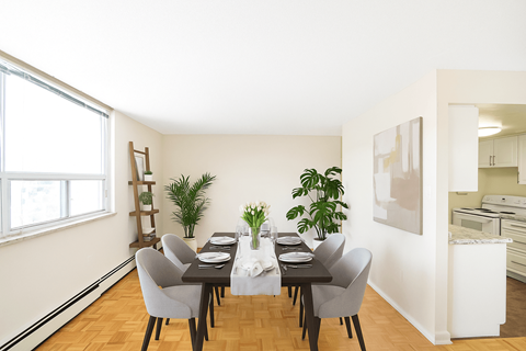 A dining room with a table set for two and a potted plant on the table.