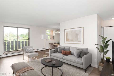 A living room with a grey couch, a coffee table, and a large window.