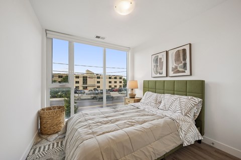 A bedroom with a large bed and a view of the street outside.