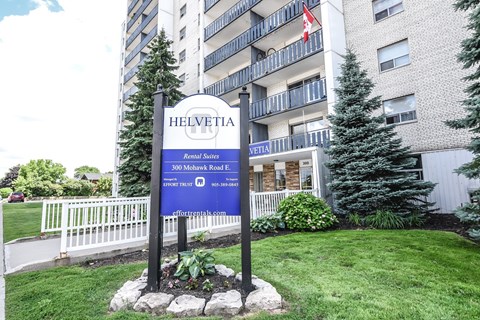 A sign for Helvetia Apartments stands in front of a building.