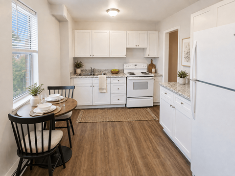 A kitchen with white cabinets and a wooden floor.