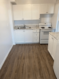 A kitchen with white cabinets and a white stove.