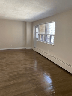 A room with wooden floors and a window with blinds.