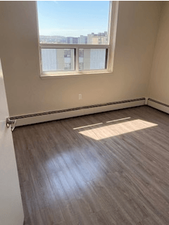 A room with a window and a view of buildings outside.
