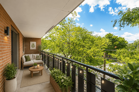 A balcony with a sofa and a table with a vase on it.