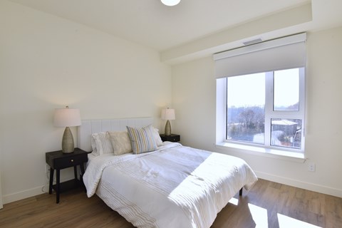 A bedroom with a large bed and two lamps on side tables at Roxy Apartments, Ontario