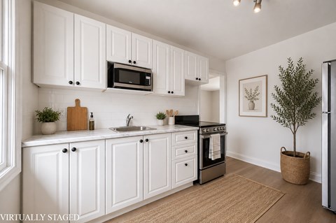 A kitchen with white cabinets and a black stove top oven.