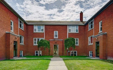 A red brick building with a green lawn in front.