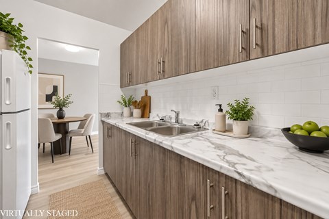 A kitchen with wooden cabinets and a marble countertop.