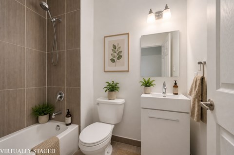 A white bathroom with a toilet, sink, and a plant.