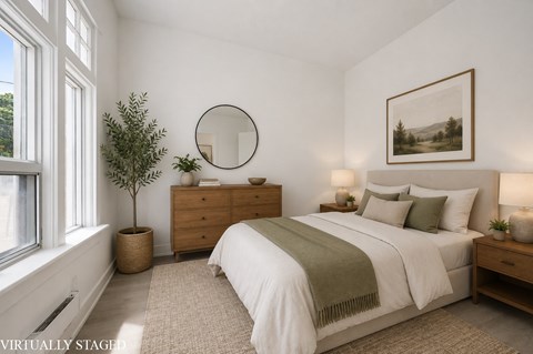 A bedroom with a large bed, a dresser, and a potted plant.