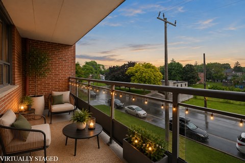 A balcony with a table and chairs overlooking a street.