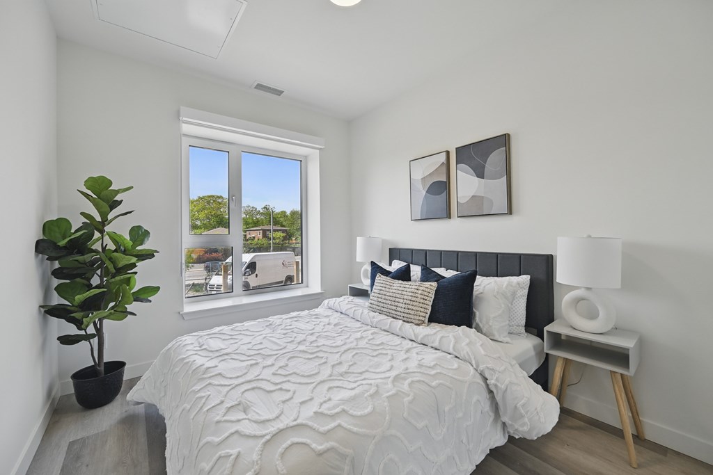 A bedroom with a large bed and a potted plant. A bedroom with a large bed and a potted plant at Roxy Apartments, Hamilton, ON