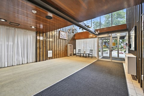 A modern interior with a wooden ceiling and a carpeted area leading to a glass door.
