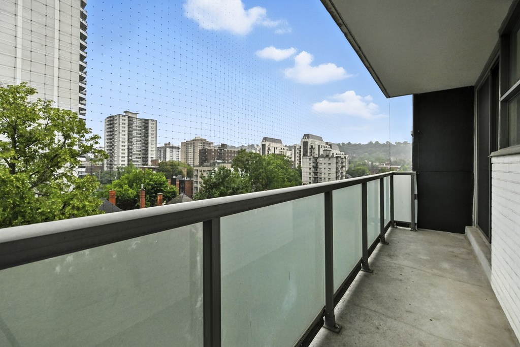 A balcony with a glass railing overlooks a cityscape.