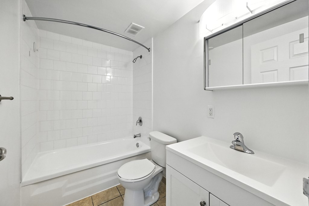 A white bathroom with a toilet, sink, and bathtub.