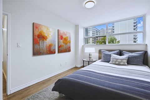 A bedroom with a large bed and two paintings on the wall.