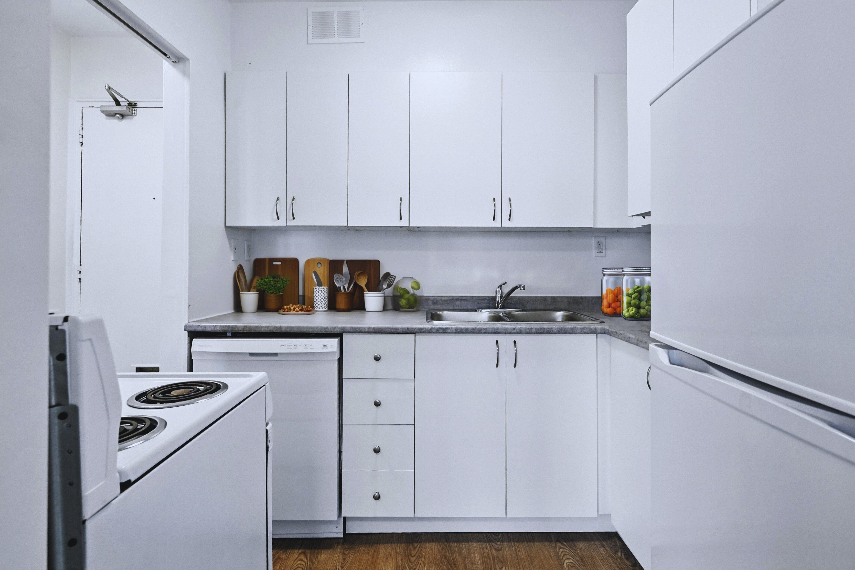 A kitchen with white cabinets and a stove top oven.