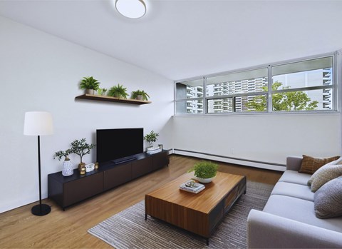 A modern living room with a flat screen TV, a wooden coffee table, and a grey sofa.