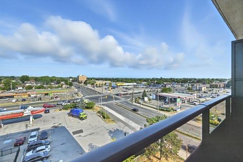 A view from a balcony overlooking a busy parking lot and road.
