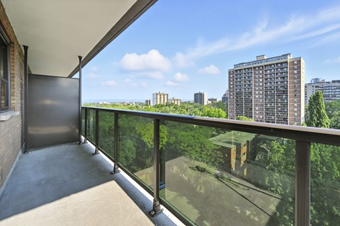 A balcony with a glass railing overlooking a cityscape.