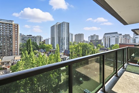 A balcony overlooks a cityscape with various buildings and trees.