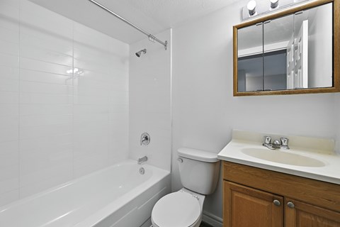 A white bathroom with a toilet, sink, and bathtub.