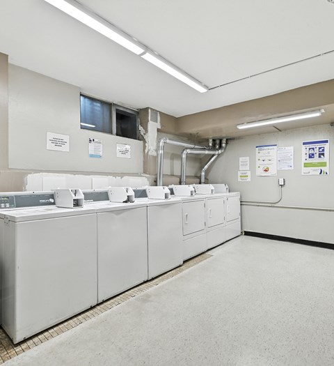 A series of washing machines are lined up in a laundromat.