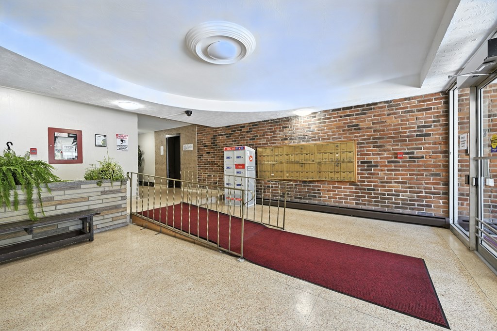 A hallway with a red carpet and a brick wall.