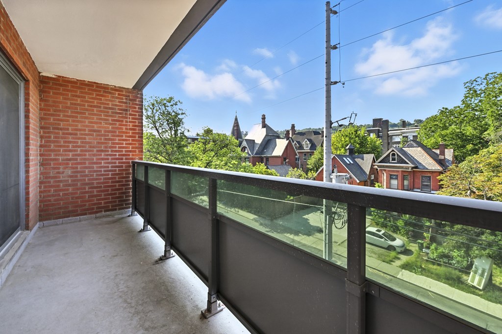 A balcony with a glass railing overlooking a residential area.