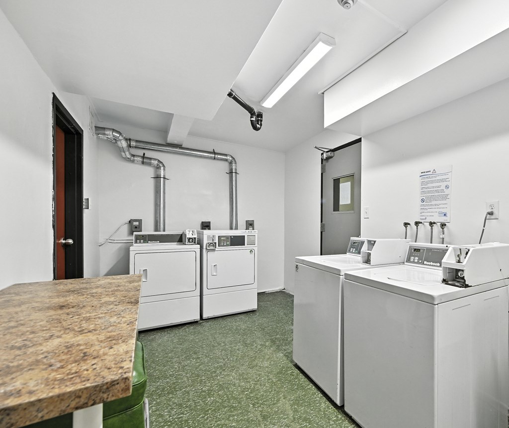 A clean, white industrial room with a green floor mat and a variety of machines.
