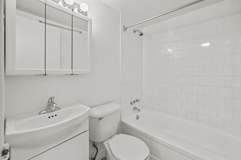 A white bathroom with a toilet, sink, and bathtub.