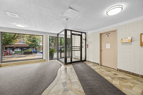 A hallway with a black door and a grey carpet.