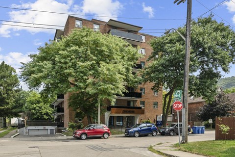 A red car is parked in front of a building with a stop sign.