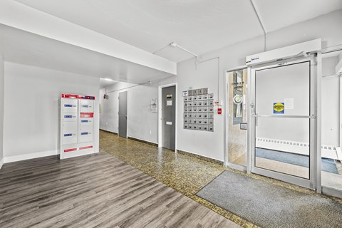 A hallway with a white wall and a door with a glass window.