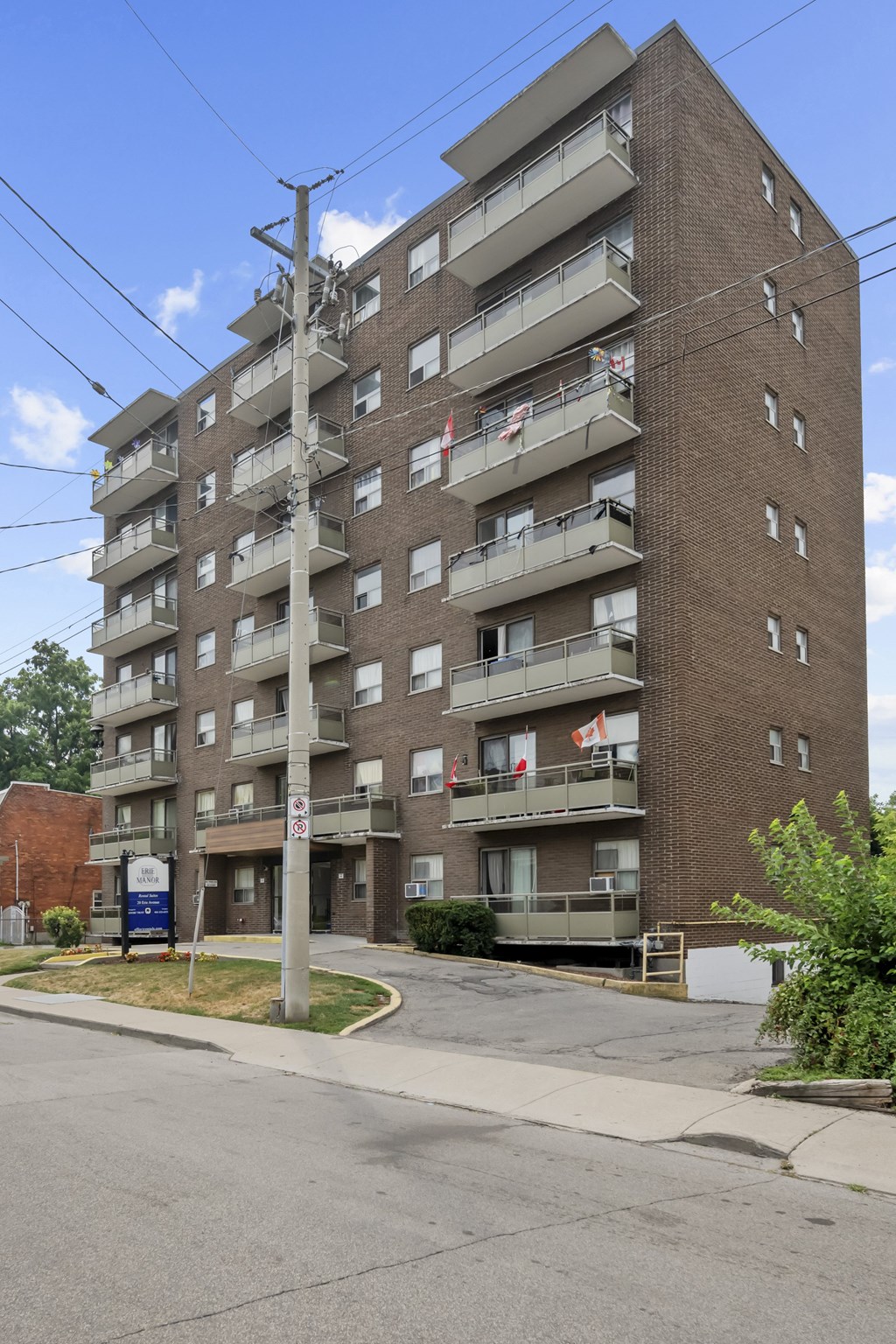 A tall apartment building with multiple balconies and flags hanging from the balconies.