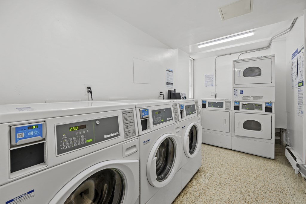 A row of industrial washing machines in a clean, white-walled room.