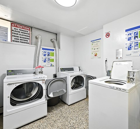 A laundromat with a sign that says "Attention all tenants please remove your clothes and dryers when finished.".