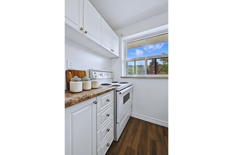A kitchen with white cabinets and a window.