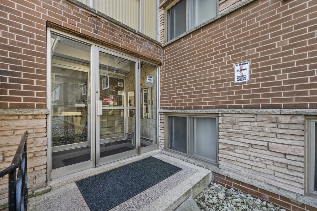 A brick building with a glass door and a sign on the wall.