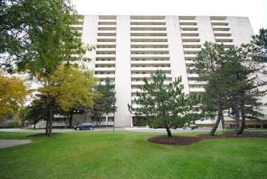 A large white building with a lot of windows and a tree in front of it.