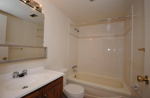 A white bathroom with a toilet, sink, and bathtub.