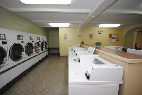 A laundromat with washers and dryers lined up.